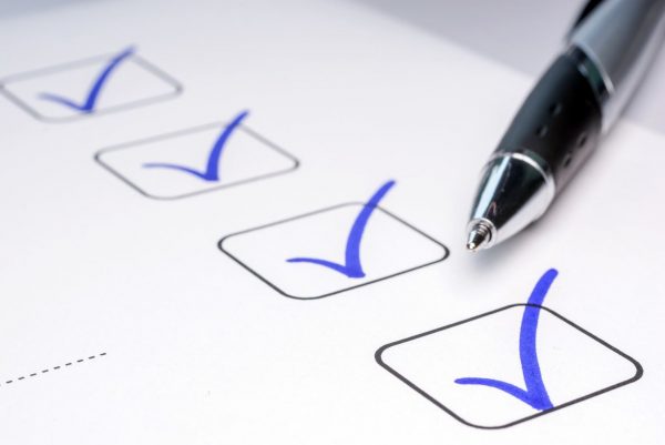 Stift mit blauen Häckchen auf Checkliste